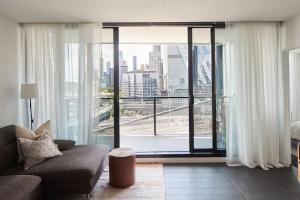- un salon avec un canapé et une grande fenêtre dans l'établissement Cityscape Trendsetter - Contemporary Chic with Pool, à Melbourne