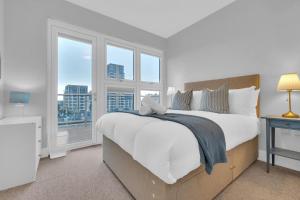 a bedroom with a large white bed with windows at Station Skyline One By My Getaways in Brighton & Hove