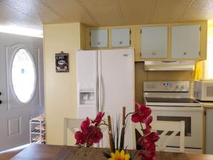 Sun Angel House #3 Pahrump في باهرومب: مطبخ مع ثلاجة بيضاء وطاولة مع ورد