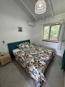 a bedroom with a bed with a comforter on it at Bungalow Ixora in Les Abymes
