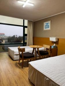 Habitación de hotel con 2 camas, mesa y sillas en Seongsan Motel en Seogwipo