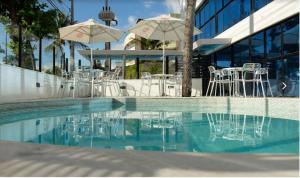 Una piscina con sillas y sombrillas al lado de un edificio. en Ambassador Flat, en João Pessoa