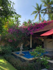een fontein in de tuin van een huis met roze bloemen bij Teluk Karang Dive & Spa Resort in Tejakula