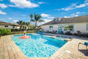 a swimming pool with an inflatable pool toy in front of a house at New Listing! Beach Walk Newly Renovated - Walk To Vanderbilt Beach! in Naples