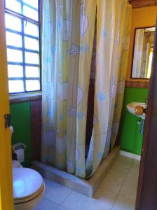 a bathroom with a toilet and a shower curtain at Sinadan in Barbosa