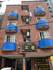 a brick building with blue balconies and a clock on it at Oreum Motel in Jeju
