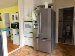 una cocina con nevera de acero inoxidable y armarios blancos en Fairmount Place, en Fair Lawn