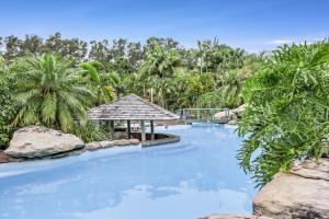 a resort swimming pool with a gazebo and trees at Oceanique in Coffs Harbour