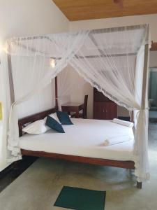 a bedroom with a white bed with a canopy at Unawatuna Backpacker Lodge in Unawatuna