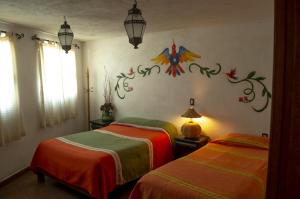 1 dormitorio con 2 camas y un mural en la pared en Posada del Fraile, en Tepotzotlán