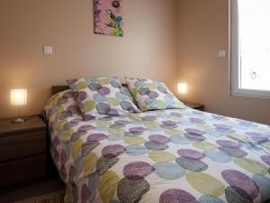 a bed with a colorful comforter in a bedroom at Spacieuse maison rénovée, nature verdoyante - FR-1-489-176 in Valigny
