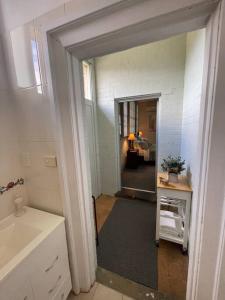 a bathroom with a hallway with a sink and a mirror at Post Office Boutique Accommodation in Hat Head