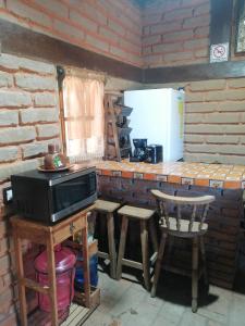 a kitchen with a counter with a microwave and stools at Cabaña El Fresno 