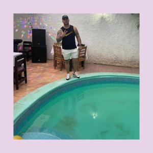 a man standing next to a swimming pool at La Mezcla Perfecta Hostal in Managua