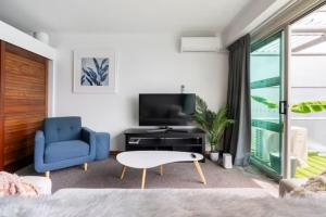 a living room with a blue chair and a tv at Luxury Hideaway On Princes Wharf in Auckland