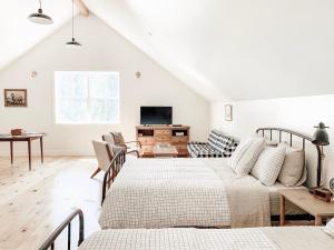 a white living room with two beds and a tv at Homestead Barn Loft in Sonora