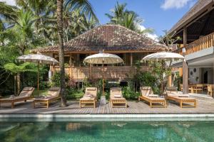 a resort with a pool and chairs and umbrellas at RUMAH KAYU RESORT in Ubud
