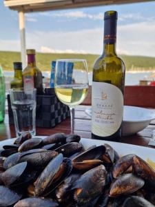 a plate of mussels and a bottle of wine and a glass at Barba Rude in Punat