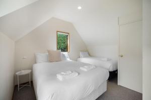 two beds in a room with white walls at Lakefront Cottage in Queenstown