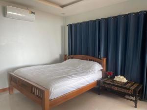 1 dormitorio con 1 cama con cortinas azules y 1 cama sidx sidx sidx sidx en บ้านระเบียงเลหลังสวน ทั้งหลัง 2 นอน 2 น้ำ 1 ครัว en Ban Hin Sam Kon