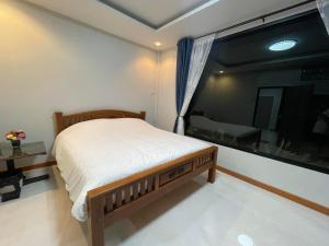 um quarto com uma cama e uma grande janela em บ้านระเบียงเลหลังสวน ทั้งหลัง 2 นอน 2 น้ำ 1 ครัว em Ban Hin Sam Kon
