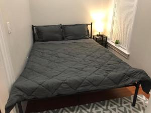 a bed in a bedroom with a gray comforter at 3 HOMESTAY At Boston In Dorchester or JFK-UMASS or South Boston in Boston