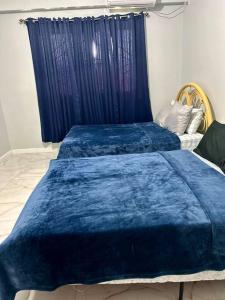 2 Betten mit blauen Decken in einem Zimmer in der Unterkunft Piarco Airport Guest House in Piarco