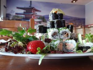 a plate of sushi and vegetables on a table at The Pop Art Apartment in Katowice