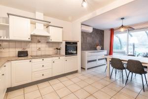 uma cozinha com armários brancos e uma mesa e cadeiras em ALPILOC - Town house with garden and winter lounge em Annecy