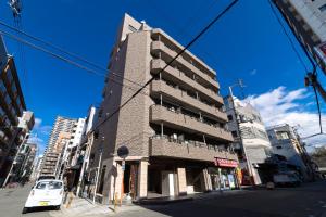 ein hohes Gebäude an der Ecke einer Stadtstraße in der Unterkunft Aoi home Nipponbashi in Osaka
