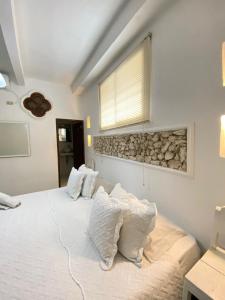 um quarto com uma cama branca com almofadas em Patio de Getsemani em Cartagena de Indias