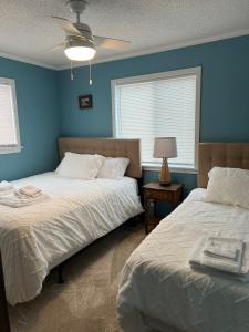 two beds in a bedroom with blue walls at Beach Please* in Carolina Beach