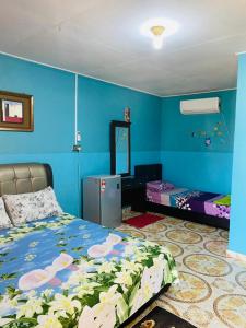 a bedroom with blue walls and a bed with flowers on it at Ella's Place Salang Tioman in Tioman Island