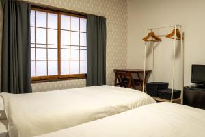 a hotel room with two beds and a window at White Lodge Fukujuso in Iiyama