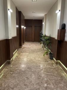an empty hallway of a building with wooden doors and plants at وحدة الملقا لاقزجري in Riyadh