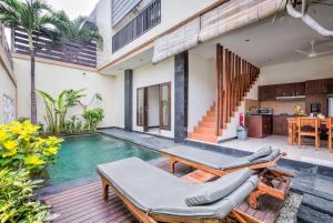 an outdoor patio with a swimming pool and a house at Villa Raka in Legian