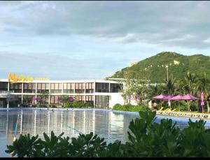 a resort with a swimming pool and a mountain in the background at Maldives B3-30 Oceanami Villas & Beach Club in Long Hai