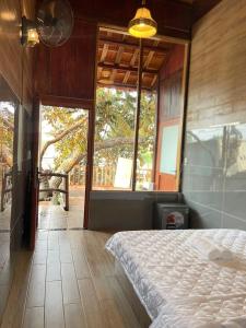 ein Schlafzimmer mit einem Bett und einem großen Fenster in der Unterkunft Cát Tiên Hotel in Cat Tien