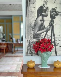 a vase with red flowers and a camera on a table at Samsara Inn in Legian