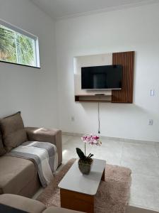 sala de estar con sofá y TV en la pared en Jacuipe Sun House, en Camaçari