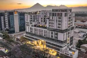 een hoog wit gebouw met een zonsondergang op de achtergrond bij Rincon Moderno cerca aeropuerto in Guatemala