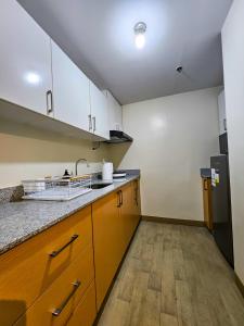 une cuisine avec un évier et un réfrigérateur dans l'établissement Brand New Central Convenience Studio Condo with Balcony in Araneta City Cubao, à Manille