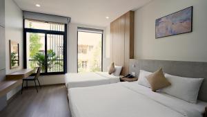 a bedroom with two beds and a desk and a window at Thành Thuý Hotel in Buon Ma Thuot