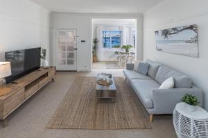 uma sala de estar com um sofá e uma televisão em Luxe-Coastal Balmoral Beachfront Apartment em Sydney