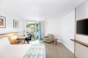 a hotel room with a bed and a tv and a desk at Holiday Inn Suva, an IHG Hotel in Suva
