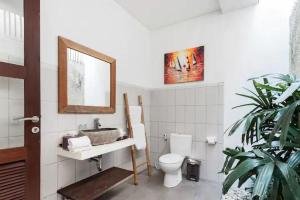 a bathroom with a toilet and a sink and a mirror at Villa Vidya Managed by Manara in Seminyak