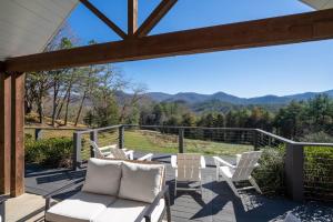 a deck with white chairs and a view of the mountains at Cottages @ Julep Farms in Dillard