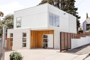 a white brick house with a wooden door at Architect Home with View in Central Hobart in Hobart