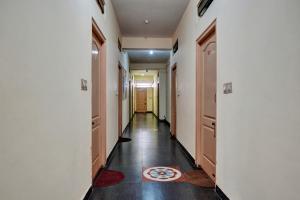 pasillo con paredes blancas, suelo de madera y puerta en OYO Flagship Jashwanth Residency en Mysore