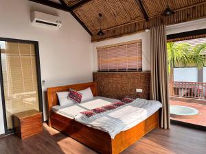 a bedroom with a bed with a window and a tub at Thang Mây Village Resort in Ba Vì
